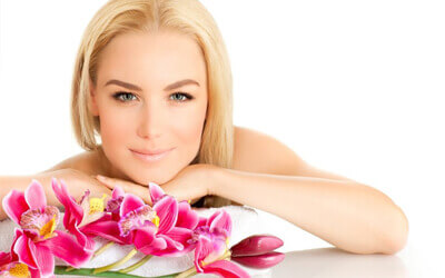 Picture of a happy woman looking at the camera and smelling the flowers